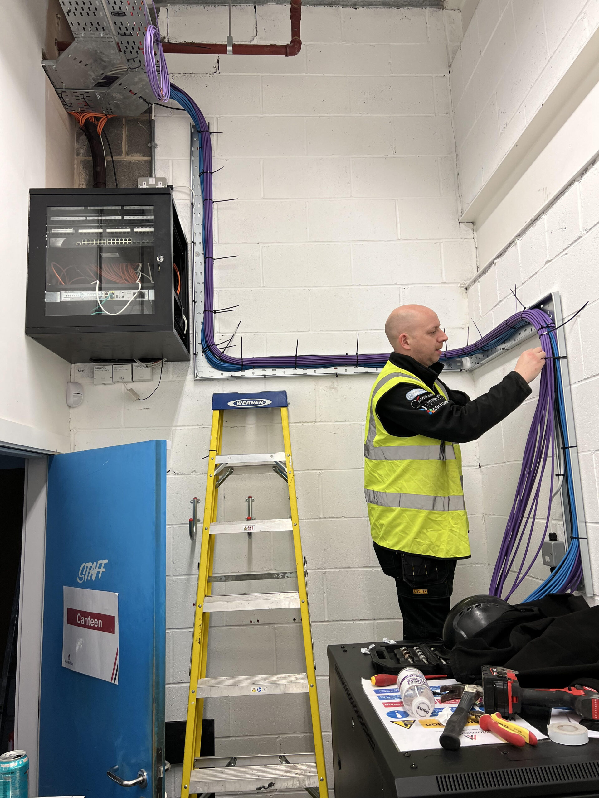 Technician performing network health check in an office, ensuring optimal performance of structured cabling and wireless systems